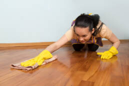 young housewife with yellow gloves cleaning floor